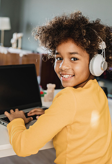 Child with headphones using computer